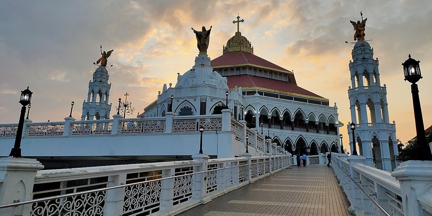Historic Edappally Church with white facade, arched windows, and a peaceful surrounding area.