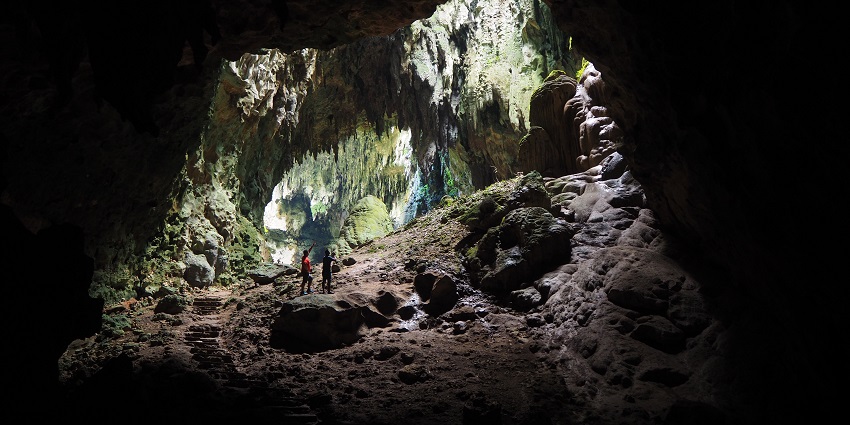A group of people exploring caves in a chamber and uncovering its natural beauty