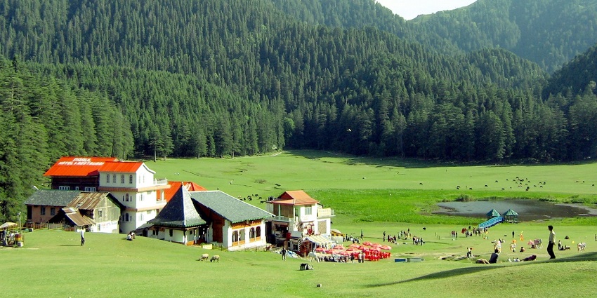 Vibrant lush fields of Khajjiar, offering a picturesque view of the forested hills beyond