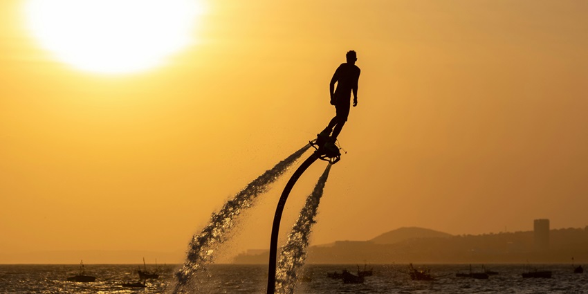 A stunning silhouette of a man flyboarding during the golden hour, a must-try activity.
