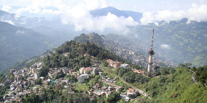 A sprawling hillside town, Gangtok, with colourful buildings nestled among lush greenery