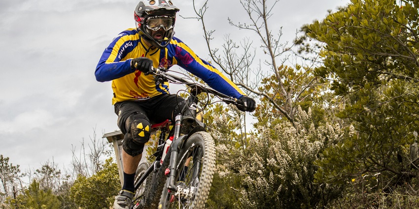 A view of a person riding through the rugged terrains on a bike surrounded by greenery.