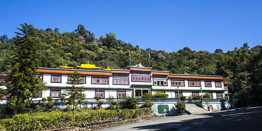 A frontal view of Rumtek Monastery with trees in the background