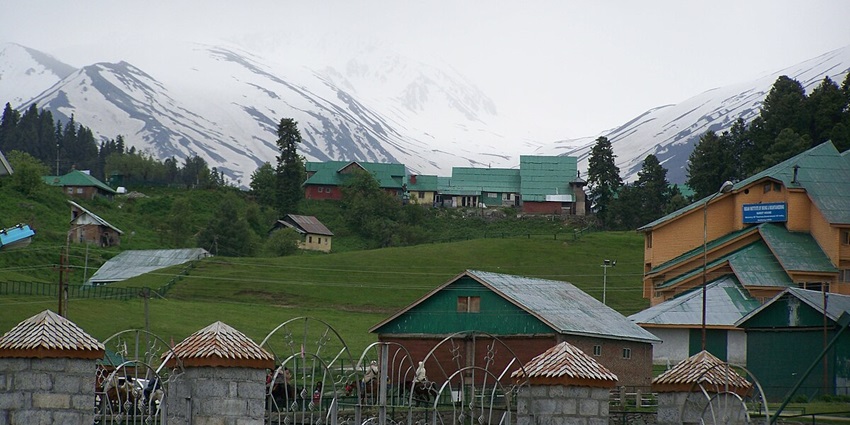 Quaint and serene houses in Gulmarg with snow capped mountains in the background.