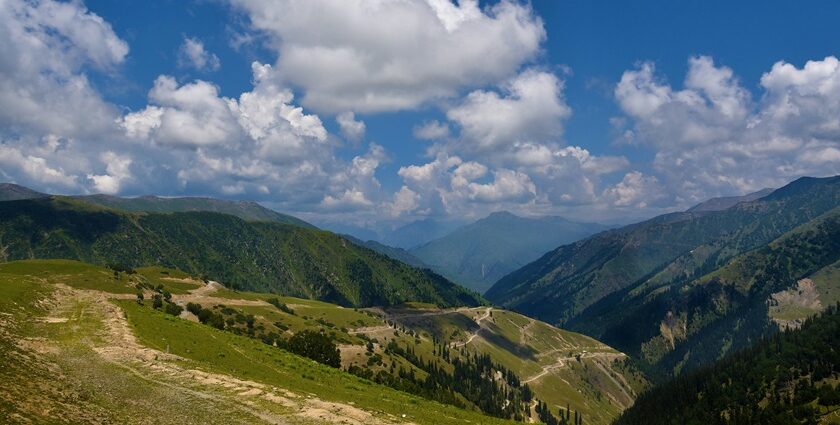 A breathtaking view of Gurez Valley with lush green hills covered under dense clouds.