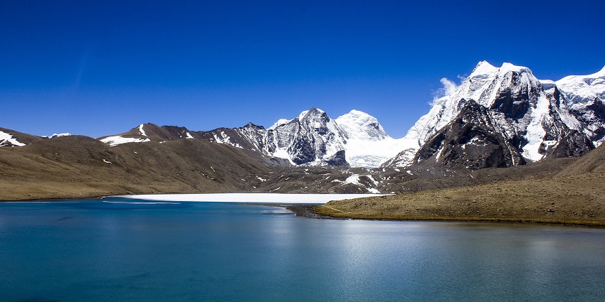 Reflections of the snowy mountains in dancing in the clear blue waters of Gurudongmar Lake