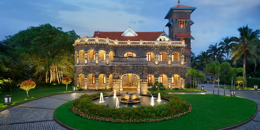 A frontal view of the resplendent Halcyon Castle, Kovalam surrounded by lush greenery.