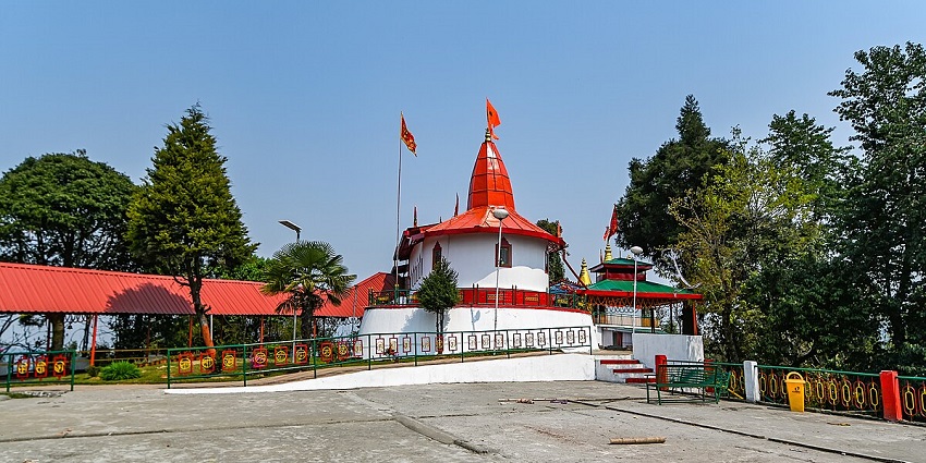 A view of Hanuman Tok with orange and white architecture surrounded by lush green trees.