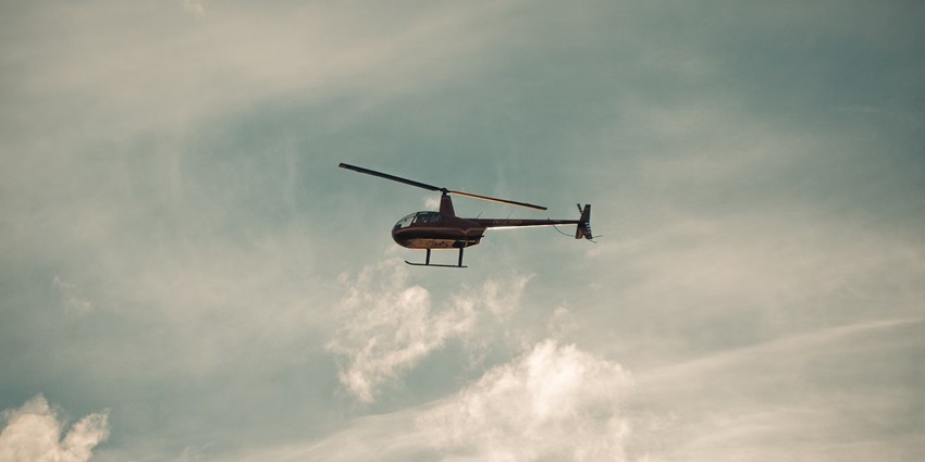 A view of a helicopter flying in the air during the daytime, an activity for travellers.