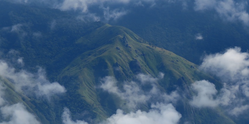 Aerial view of the Messapulimala summit through the clouds and dense forest