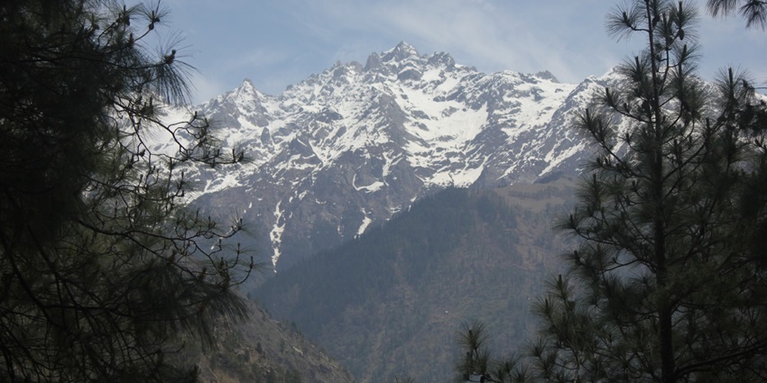 Stunning view of the Himalayas from Kasol, with snow-capped peaks and clear skies.