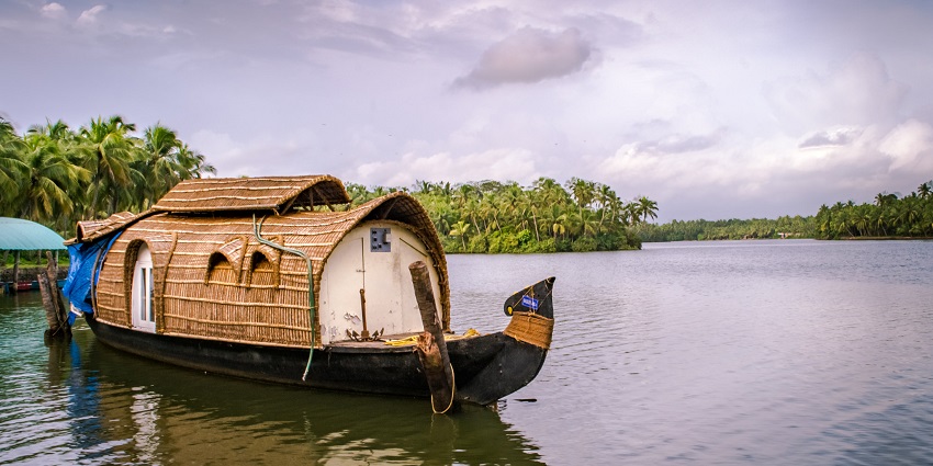 View of a houseboat cruising through tranquil backwaters, surrounded by lush greenery.