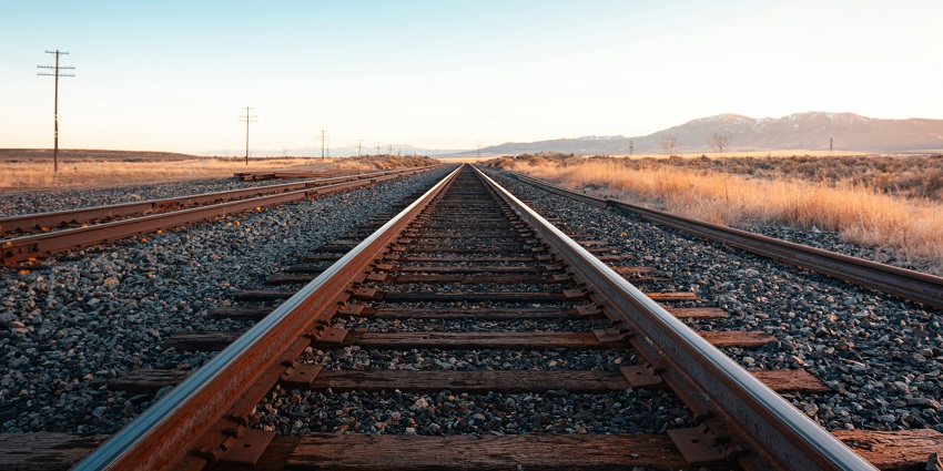 A unique view of a railway track with enormous mountains at a distance in the backdrop.