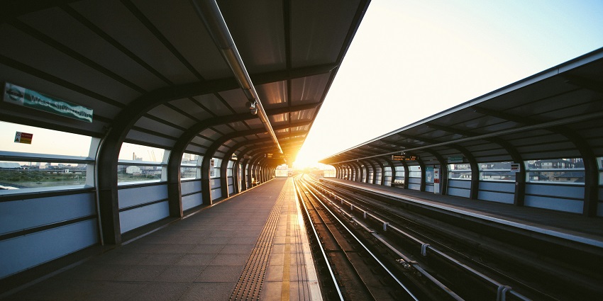 A distant view of a railway track with the sun beaming brightly in the background.