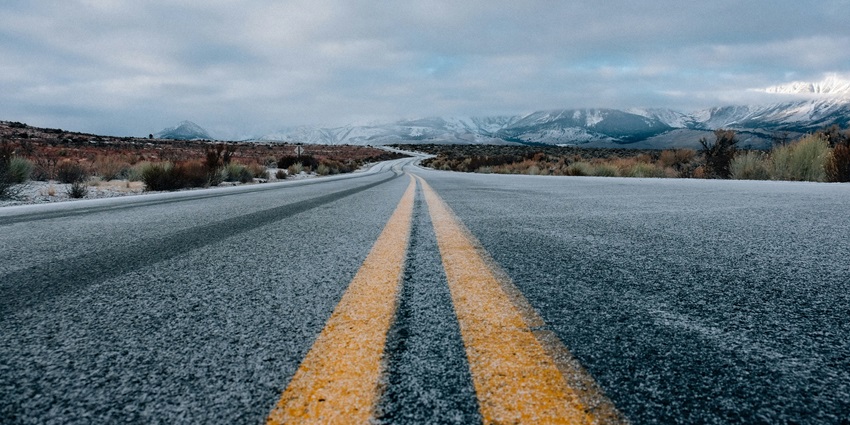 A view of a straight road leading up to the mountains surrounded by lush green grass.