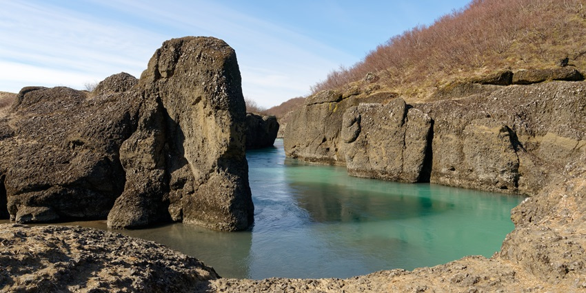 A picture of a cliff in Iceland with a beautiful river flowing through the area
