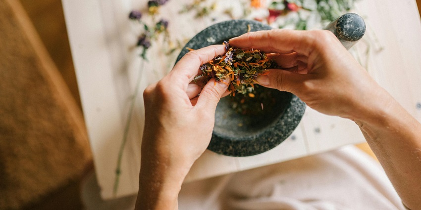 Top View of Woman Mixing Herbs in Mortar - Indulge in Ayurvedic Treatments