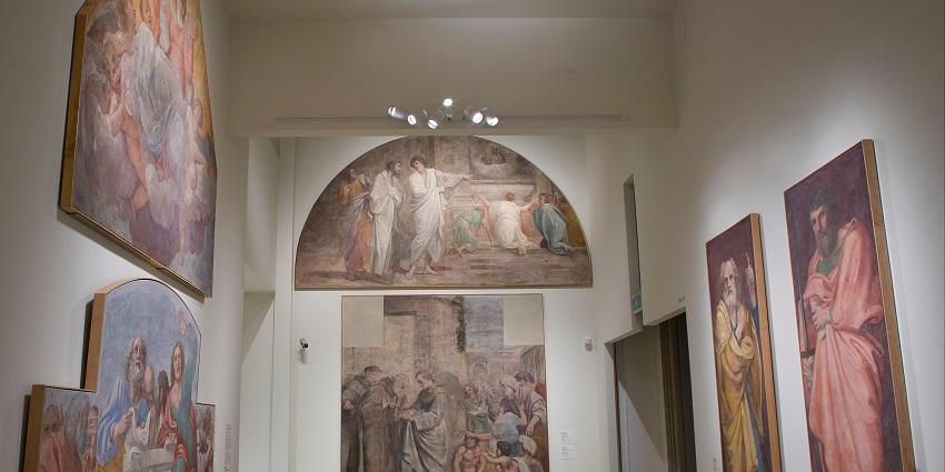 A picture of a gallery with numerous paintings put up for display in a well-illuminated ambience