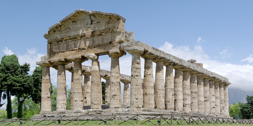 A picture of a historical monument, the Temple of Athena, in Italy with rock structures and greenery