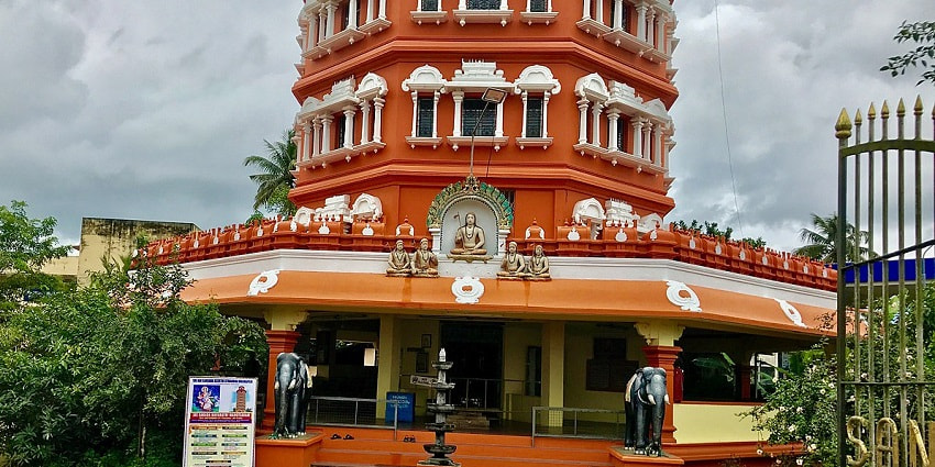 A mesmerising view of a temple in Kalady with orange walls and elephant statues in front.