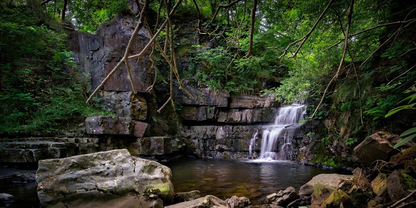 Crystal-clear waterfall flowing into a serene natural rock pool, rendering a mesmerising landscape.