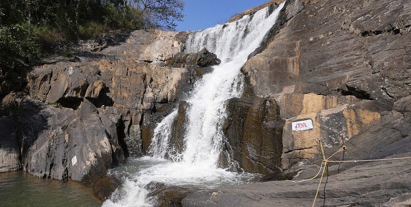 A breathtaking view of Kanthanpara Waterfalls in Kerala surrounded by lush green trees.