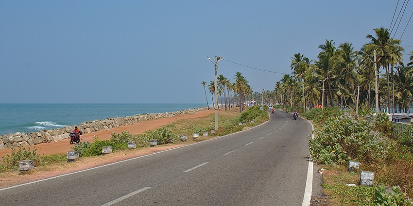 Scenic Kappil Beach Road with ocean views on one side and lush greenery on the other.
