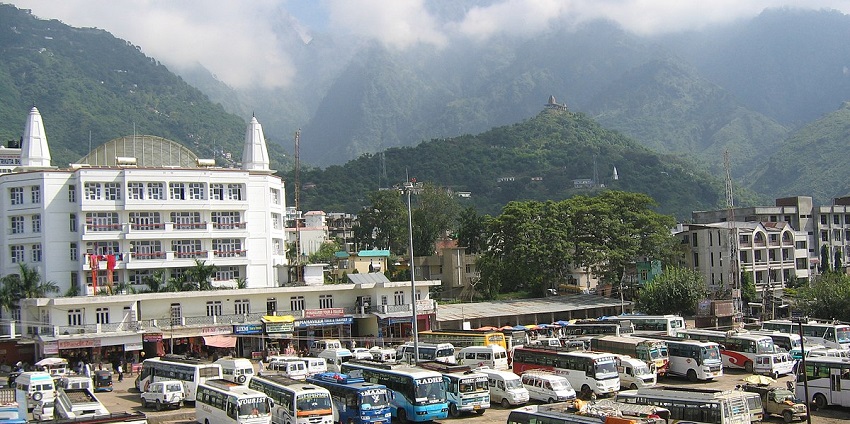 A view of Katra bus stand with lush green mountains and cloudy skies in the background