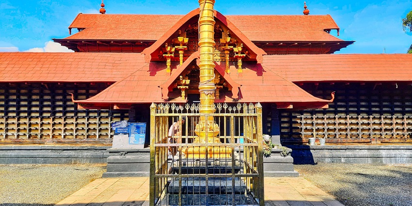 A frontal view of a historical Shiva temple with a tall golden stupa in front of it
