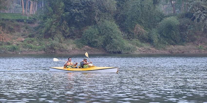 Two men enjoying kayaking & exploring nature with a view of dense forest in the background