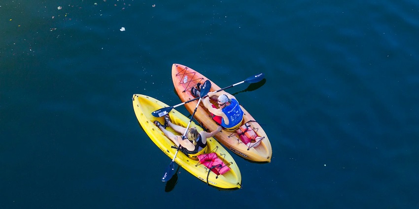 An aerial view of two kayaks with a man and woman on it with paddles in their hands.