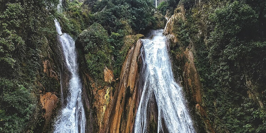 Water cascading down rocky steps in a lush setting - one of the best waterfalls in India