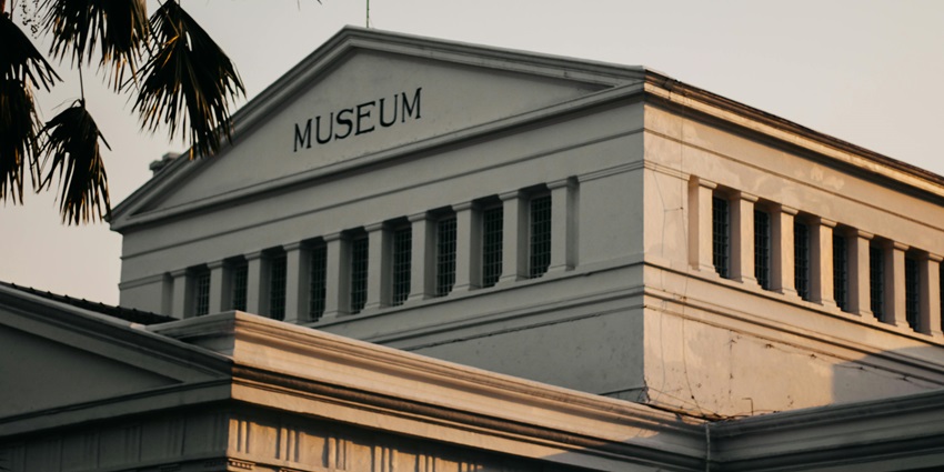 Low-angle view of a white museum building glowing in golden hour sunlight.