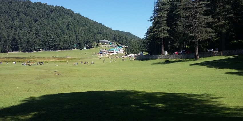 A picture of a lush green valley with views of tall peaks in the background