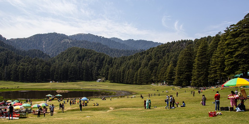 A group of people atop a lush green hill in Khajjiar that is often termed “mini-Switzerland”
