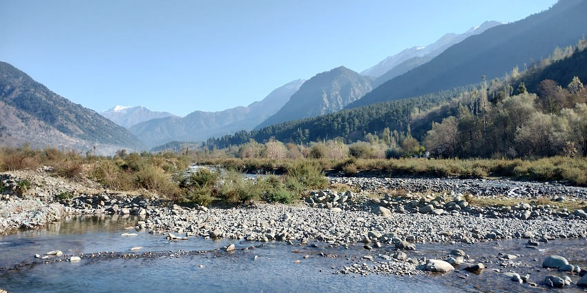 Curving mountain scenes in Kashmir, surrounded by green patches and rocky slopes