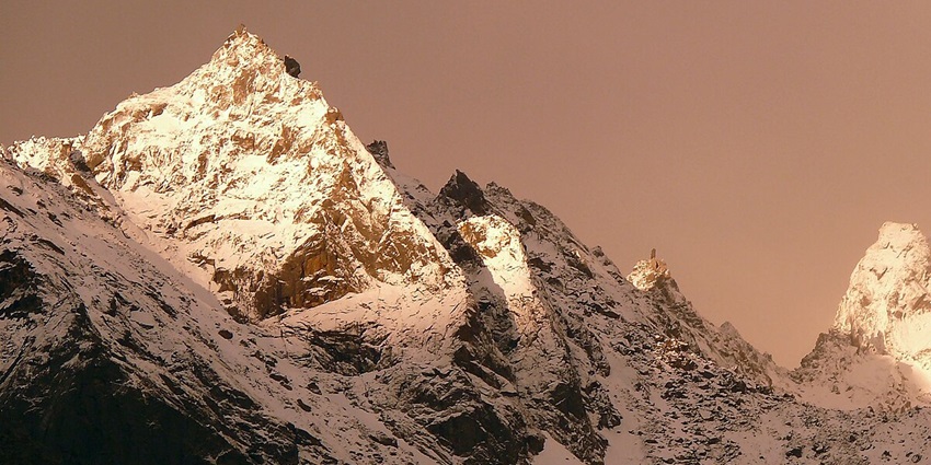 A scenic view of snow-covered Mount Kinner Kailash with sunlight falling over its top