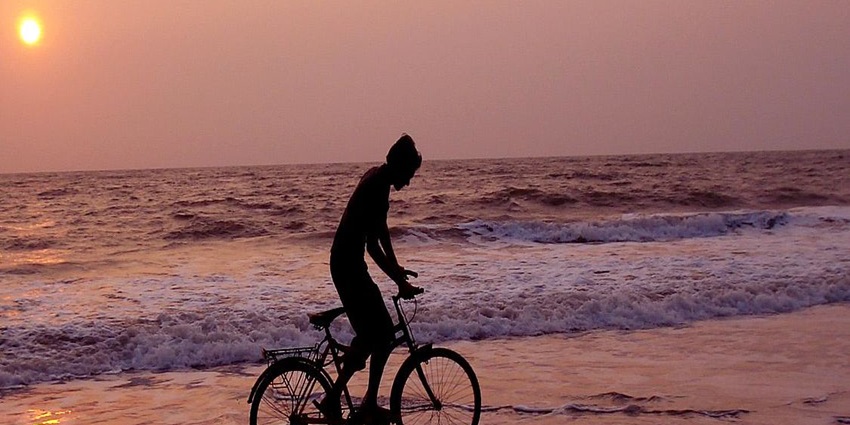 Man cycling on the iconic Kizhunna beach during the sunset on the beach of Kannur