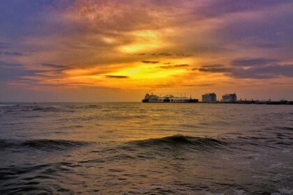 A breathtaking view of a water body in Kochi during sunset near white buildings.