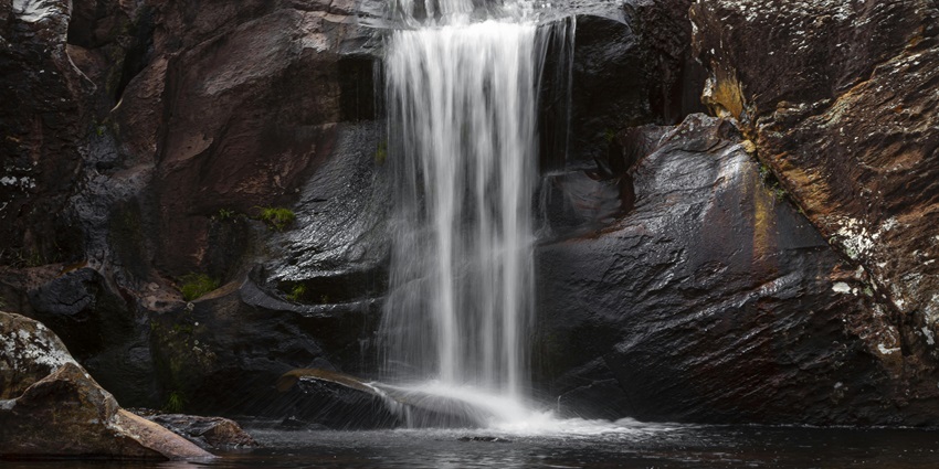Photo Of waterfalls During Daytime - surrounded by huge rocks cascading clear water