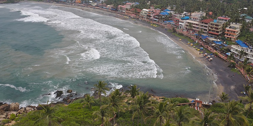 Picturesque Kovalam Beach with golden sands and waves crashing against the shore.