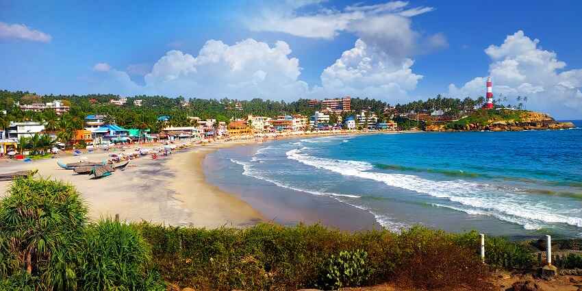 Scenic Kovalam Beach with golden sands, clear blue waters, and swaying palm trees.