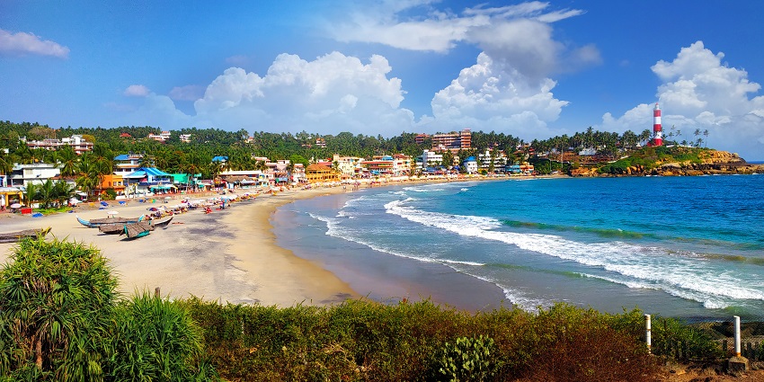 Scenic view of Kovalam beach clear blue water, blue sky, and surrounded by lush greenery