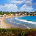 A scenic glimpse of azure waters hitting the sandy shores at Kovalam Beach in Kerala.