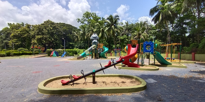 Children’s play area with slides and swings near Vazhani Dam surrounded by trees.