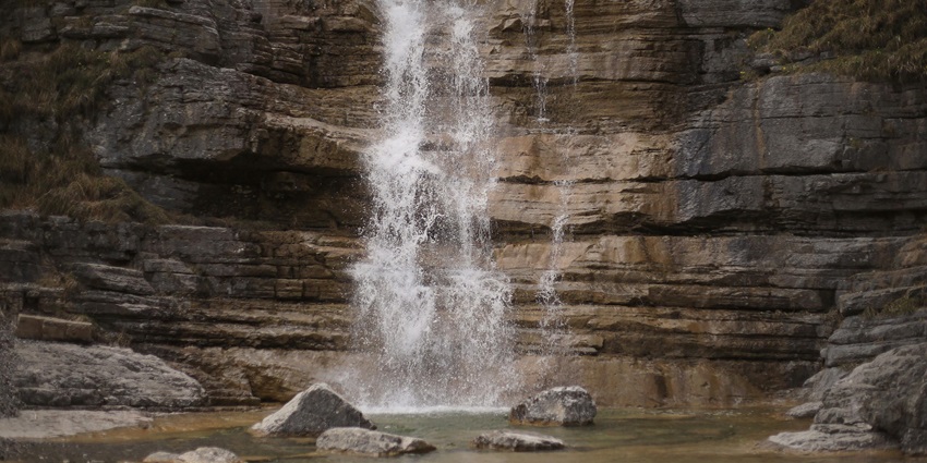 Majestic waterfall cascading through dense forest in tropical mountain setting.