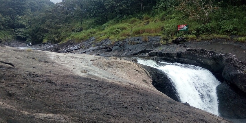 Waterfall surrounded by dense green forest and rocky terrain - waterfalls in Kozhikode