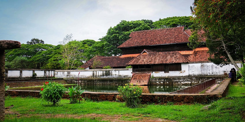 A frontal view of a historical palace in Alleppey with a blanket of lush greenery all around