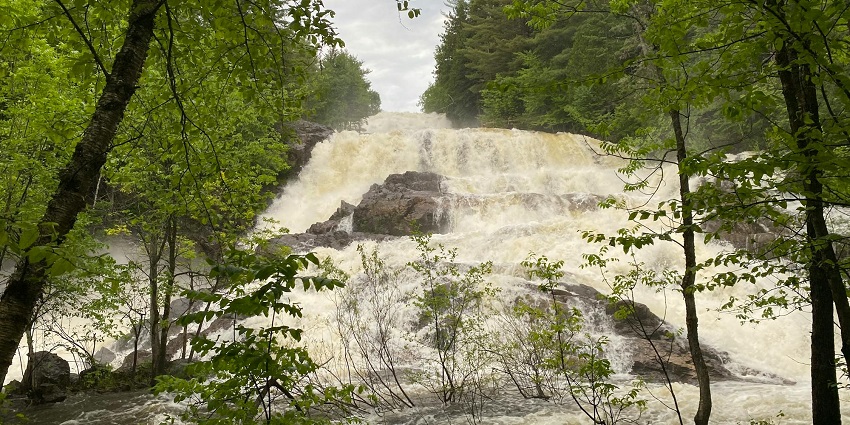 The breathtaking view of a waterfall cascading down rocky steps amid lush surroundings