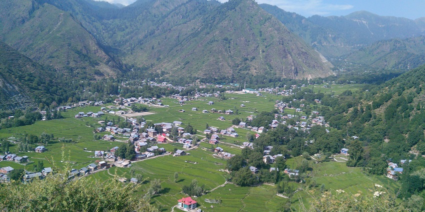View of Kupwara Valley with several scattered houses surrounded by high mountain peaks.